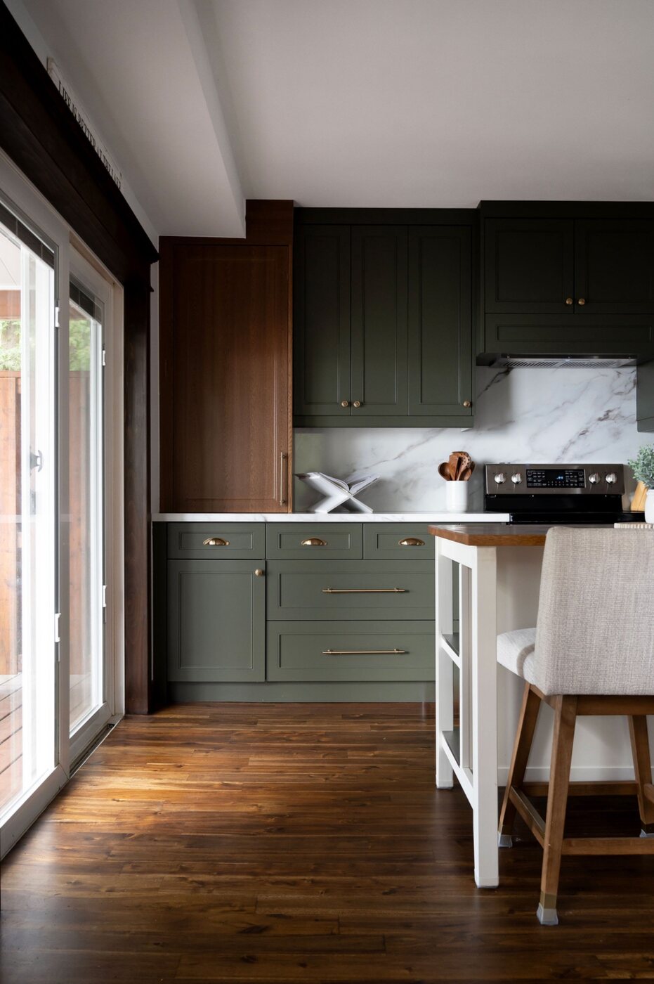 Renovated kitchen with green cabinetry, wood floors and breakfast island